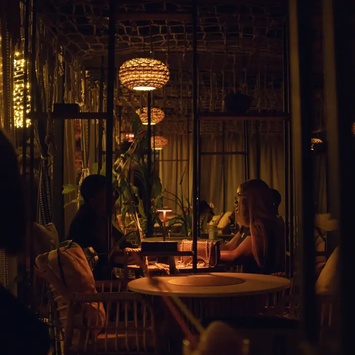 Guests dining at night beneath rope and plants in The Shrine